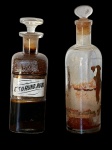 Dois  antigos vidros  de farmácias de diferentes formatos com tampa, lacrado , contendo produtos farmacêuticos dentro deles