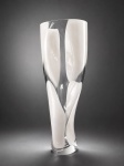 LINA BERGSTEN - Vaso artístico em cristal sueco Orrefors, assinado por Lina Bergsten. Datado de 1998. Elegante composição em vidro translúcido com aplicações orgânicas em branco leitoso fusionadas à massa, apresentando desenho escultórico de forte caráter contemporâneo. Destaca-se pela fluidez das formas, pureza do cristal e refinado domínio técnico característico da tradicional manufatura sueca Orrefors. Peça assinada Lina Bergsten e marcada Orrefors Sweden na base.