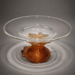 FRANCE - Centro de mesa francês DAUM, em cristal artístico de excepcional qualidade, apresentando elegante copa translúcida apoiada sobre base escultórica em pâte de verre, em delicado degradê âmbar.A composição revela o refinamento característico da célebre manufatura francesa, com modelagem orgânica inspirada na natureza, rica textura e notável efeito luminoso proporcionado pelo trabalho artesanal do cristal.