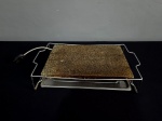 Chapa para cozimento, elétrica, confeccionada em pedra, apoiada em suporte de metal prateado, acondicionada em caixa original. Obs: Sem uso. Med.: 50 x 28 cm.