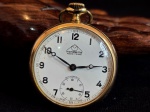 MONDAINE - Antigo relógio suíço de bolso, caixa confeccionada em plaque dor, metal banhado a ouro, mostrador em porcelana esmaltada na cor branca. Diâmetro. 50 x 40 mm. Funcionando. Peso: 52 Gramas. (Total).