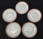 Renner. Cinco pratos para sobremesa em porcelana esmaltada, decorado com listra vinho e ouro, sob fundo branco. Manufatura no verso. Medindo; 17,5 cm. 