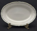Vista Alegre, Portugal. Edição especial Confeitaria Colombo. Travessa oval em porcelana portuguesa esmaltada, decorada com listras verde e filetes em ouro sobre fundo branco. Borda ondulada. Manufatura no verso. Medindo; 41 x 28 cm. Apresenta desgastes. 