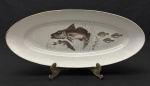 Rio Branco. Grande travessa em porcelana nacional esmaltada, decorado com peixes e algas sobre fundo branco e filetes em ouro.Manufatura no verso. Medindo: 6 x 59 x 26cm.