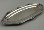 Fracalanza. Belíssima travessa oval em metal espessurado à prata, da afamada manufatura Fracalanza, modelo lacinho. Borda ricamente cinzelada. Medindo: 52,5 x 23,5 cm. Apresenta marcas de uso. 