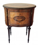 Mesa lateral estilo Luís XVI, em madeira com rica marchetaria floral e filetagens, tampo oval com decoração central, duas gavetas frontais e aplicações em bronze. Apoiadas sobre pés finamente torneados. Medidas: 71 x 45 x 57 cm.