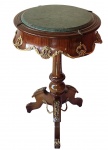 Mesa auxiliar estilo Império, em madeira com tampo circular em mármore verde, ricamente adornada com aplicações em bronze dourado. Corpo recortado com ornamentos em relevo e coluna central torneada, apoiada sobre base tripé. Medidas: 73 x 44 x 44 cm.