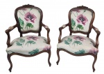 Par de poltronas estilo francês Luís XV, em madeira entalhada, com espaldar ovalado, braços curvos e pernas cabriolés. Assentos e encostos estofados em tecido floral, finalizados com tachas decorativas. Medindo: 93 x 63 x 57 cm.