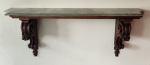 Console de parede em madeira entalhada, com elegante tampo em mármore de tonalidade esverdeada e veios marcados. Estrutura sustentada por mãos-francesas ornamentadas com volutas, frisos perolados e elementos vegetalistas em relevo, revelando influência clássica europeia de inspiração neorrenascentista/francesa. Medindo: 57 x 143 x 30 cm.
