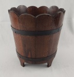 Charmoso cachepot confeccionado em madeira, com borda recortada em formato ondulado e acabamento em tom natural escuro. Estrutura reforçada com cintas metálicas, conferindo resistência e um visual rústico de inspiração europeia. Apoiado sobre base elevada com pés recortados, apresenta bom volume interno, podendo ser utilizado como jardineira, porta-vasos ou elemento decorativo. Medindo; 29 x 27,5 cm. 