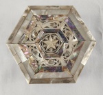 Delicada caixa porta-joias em formato hexagonal, ricamente revestida em madrepérola com belos reflexos iridescentes. Tampa decorada com entalhes e composição geométrica, evidenciando trabalho artesanal de inspiração oriental. Interior forrado em tecido. Medindo; 5 x 13 cm. 