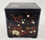 Elegante caixa porta-objetos em laca oriental, de formato retangular, com tampa e 3 compartimentos Decorada com delicados motivos florais e elementos geométricos em policromia, sobre fundo preto, evocando a estética oriental tradicional. Medindo; 19 x 20 cm. 