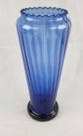 Imponente Vaso decorativo em vidro na tonalidade azul cobalto, com corpo alongado e superfície canelada. Apresenta borda ondulada e base circular. Medidas: 33 x 14 cm. 