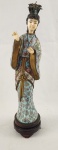 Escultura decorativa representando figura feminina oriental, com vestes ricamente ornamentadas em policromia e detalhes florais de metal de cloisonné. Apresenta base oval e adorno elaborado na cabeça, com acabamento minucioso. Peça de estilo oriental. Peanha em madeira colada a escultura. Medida total: 25 cm.