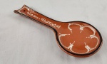 Descanso de colher em cerâmica vitrificada, na tonalidade terracota, com decoração em pintura branca e inscrição `Viseu Portugal`. Peça de formato funcional com orifício para fixação, ideal para uso culinário ou decoração. Medidas: 16 x 11 cm. 