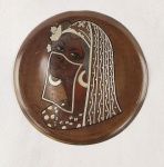 Medalhão decorativo em metal, com representação de figura feminina estilizada em relevo e acabamento patinado. Apresenta composição artística com detalhes gravados e contraste de tonalidades. Medida: 24 cm de diâmetro. 