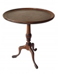 Mesa auxiliar antiga em madeira nobre, de formato circular, com tampo liso e base central torneada apoiada sobre três pés recurvos. Medidas: 50 x 46 x 46 cm.