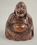 Escultura decorativa em madeira entalhada representando figura de Buda sorridente, com acabamento polido e pátina natural. Peça de pequeno porte. Medidas: 5 x 4 cm.