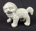 Escultura decorativa em porcelana esmaltada em tom verde celadon, representando cão estilizado com acabamento em relevo. Medidas: 8 x 13 cm.