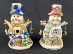 Par de castiçais em porcelana esmaltada, marca Santini (Itália), em formato de bonecos de neve estilizados, com rica decoração policromada e detalhes em relevo. Apresentam compartimento interno para vela, com aberturas decorativas. Medidas: 18 x 7 cm cada