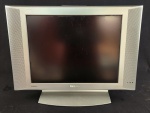 Televisor Philips Flat TV com tela LCD, acabamento na cor prata e alto-falantes integrados nas laterais. Acompanha base original. Possui conexões traseiras para áudio e vídeo. Ligando.