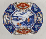 Travessa octogonal em porcelana japonesa Imari, produzida para a Takahashi San Francisco, decorada em policromia sob predominância de azul, vermelho-ferroso e dourado. Apresenta paisagem oriental ao centro e reservas florais características da tradição Imari. Verso com marca de exportação Takahashi San Francisco  Made in Japan. Medindo: 6,5 x 30 x 25,5 cm.