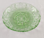 Prato decorativo em vidro prensado na tonalidade verde-clara, ricamente ornamentado com desenho geométrico em relevo, destacando estrela central multifacetada e borda recortada. Medidas: 23 cm de diâmetro.