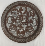 Grande prato medalhão decorativo de parede em cobre e metal gravado, ornamentado com rica composição inspirada na arte do Antigo Egito. Apresenta figura central em carruagem, rodeada por medalhões com representações de faraós, esfinge, pirâmides e personagens da mitologia e história egípcias. Borda decorada com motivos geométricos repetitivos.Diâmetro: 50 cm.