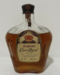 Whisky canadense Seagram's Crown Royal Fine De Luxe. Exemplar vintage produzido por Joseph E. Seagram & Sons, Waterloo, Ontário, Canadá. Garrafa em vidro moldado com decoração em relevo, rótulos originais e selo fiscal antigo, indicando comercialização na década de 1960. Peça de interesse para colecionadores de bebidas e memorabilia. Conteúdo não atestado.