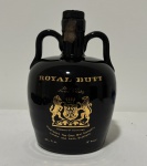 Royal Butt De Luxe Scotch Whisky. Antigo whisky escocês blended produzido pela The Glen Mist Company, com indicação de procedência de Londres e Leith, Escócia. Acondicionado em característica garrafa cerâmica esmaltada em preto brilhante, com alças laterais integradas ao corpo e decoração em dourado com brasão heráldico. Exemplar de apresentação diferenciada, bastante apreciado por colecionadores de garrafas e bebidas vintage, mantendo lacre aparente e conteúdo preservado no interior da garrafa opaca. Conteúdo não atestado. Tampa solta.