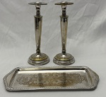 Par de castiçais da marca Eberckok e bandeja para rocambole em metal espessurado à prata. Medindo: 24 cm e 33 x 14 cm. Apresentam desgaste no banho.