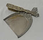 Conjunto composto por pá e espátula para migalhas, em metal espessurado a prata, ricamente ornamentados com relevos florais e arabescos, apresentando delicado trabalho decorativo nos cabos e bordas. Medindo: 20 x 14,5 cm e 21 cm. Apresenta desgaste no banho.