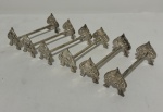 Conjunto com 6 descansos para talheres em metal espessurado a prata, em formato de naipe de espadas, ornamentados em relevo com motivos florais e concheados.