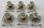 PRATA. Conjunto com 6 xícaras para café em porcelana branca, acompanhadas de suporte para xícaras, pires e colheres em prata de lei contrastada, ricamente trabalhados em delicado detalhes vazado, ornamentados com medalhões centrais representando brasões de Portugal coroado. Um xícara com bicado. Peso total peças em prata.; 587 gramas.