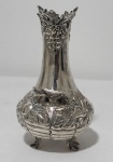 Antiga floreira/ vaso solifleur em metal espessurado à prata, de formato bojudo com colo alongado, ricamente ornamentado em relevo com cachos de uvas, folhas de parreira e delicada ave aplicada, apoiado sobre três pés estilizados em forma de folhas. Borda recortada com decoração em relevo. Medidas: 12 cm de altura.