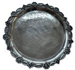 Antiga salva em metal espessurado a prata, centro ricamente gravado com delicados motivos florais e arabescos entrelaçados. Borda recortada e moldurada, ornamentada em relevo por reservas. Verso provido de três pés de apoio. Medidas: 3,5 x 30 cm.