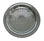 Antiga salva em metal espessurado a prata, centro ricamente gravado com exuberantes arabescos, concheados e elementos florais em delicado trabalho de buril, formando elegante composição central. Medidas: 38 cm de diâmetro.