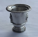Mini urna vintage em metal espessurado a prata com borda cinzelada por friso torcido, corpo liso e aplicações laterais em relevo representando cabeças de leão com argolas móveis. Apresenta desgastes. Medidas: 8 x 7,5 cm.