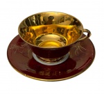 Antiga xícara para chá de coleção em porcelana esmaltada em tom bordô, interior integralmente dourado e decoração em delicados motivos florais estilizados em ouro. Alça moldada e bordas filetadas a ouro. Marca no verso.