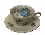 Bavaria. Antiga xícara para chá de coleção em porcelana branca esmaltada, decorada com flores policromadas em tons de azul e delicados ramos em policromia, apresentando relevo moldado na aba do pires. Alça moldada, bordas recortadas e filetadas a ouro. Marca da manufatura no verso.