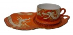 Antiga xícara de coleção em porcelana japonesa, estilo Dragonware (Moriage), acompanhada de Tea & Toast Tray (prato de apoio para chá e torradas), ricamente ornamentada com dragões orientais em relevo, realçados por esmaltação branca e douração sobre fundo vermelho alaranjado com delicados arabescos. Bordas e acabamento filetados a ouro. Manufatura no verso. Medidas: 21 x 12 x 6 cm. Discretissimo bicado.