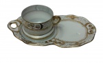 Antiga xícara de coleção em porcelana, acompanhada de Tea & Toast Tray (prato de apoio para chá e torradas), finamente decorada com delicados motivos geométricos em azul e dourado, intercalados por reservas ornamentais estilizadas. Bordas recortadas e acabamento integralmente filetados a ouro. Manufatura no verso. Medidas: 21,5 x 12,5 x 6 cm.