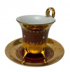 Polovi. Paraná.  Antiga xícara de coleção em porcelana, ricamente ornamentada com ampla douração e faixa em vermelho-rubi, decorada com delicados arabescos e motivos florais em reserva,  sobre 4 pés. Alça dourada e bordas filetadas a ouro. Manufatura marcada na base.