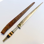Cutelaria - Antigo punhal nordestino, lâmina em aço, cabo torneado em anéis em osso, baquelite e metal  com bainha em couro. Med 29 cm. 