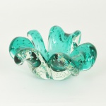 MURANO, um (1) antigo cinzeiro no formato de trevo, incolor e translucido, sulfitos na tonalidade verde, interior com bulicados, medindo aproximadamente 16 x 16 cm, sinais de uso, vide foto.