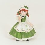 BISCUIT, uma (1) escultura figurativa policromada representando menina com vestido verde, dedos da mão quebrados e colados, medindo 10 cm altura, vide foto.