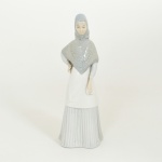 ESCULTURA, uma (1) figurativa feminina representando mulher de vestido e lenço na cabeça, policromada em tons pasteis, marca PORCELANAS MIQUEL REQUENA S. A. - VALENCIA  Made in Spain, medindo 24,5 cm altura, vide foto.