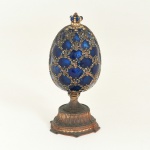 BRONZE, uma (1) escultura inspirada no ovo de Fabergé (joalheria fundada em 1842, mundialmente famosa pelos ovos criados para os Czares Russos), ao abrir representa um palácio no interior, encimado por coroa, detalhes em strass, esmaltação policromada, fecho imantado, medindo 12,5 cm altura, vide foto.