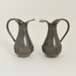 PEWTER, par (2) pequenas galhetas com ornamentação relevada, inspirada nas antigas civilizações Pré Colombianas, marca CARSU (Industria Boliviana), medindo 8 cm altura, uma delas com mossa na borda, sinais de uso, vide foto.