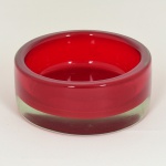 VIDRO, um (1) recipiente cilíndrico, grosso, incolor e translúcido com sulfitos ou esmaltação na parte interna na tonalidade vermelha, medindo 13 cm diâmetro e 5,5 cm altura, sinais de uso, vide foto.